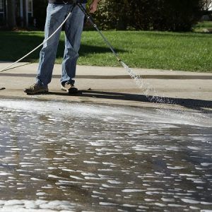 Man Washing Road With Pressure Washer