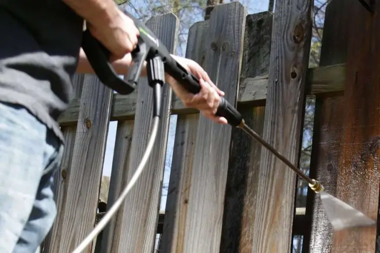 Man Washing Wooden Fence With Pressure Washer
