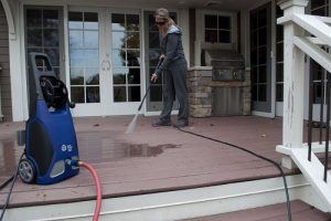 woman washing patio with a an electric pressure washer